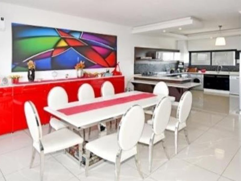Spacious open-plan living and dining area featuring modern tiled floors, recessed lighting, and a sleek, well-equipped kitchen with integrated appliances.