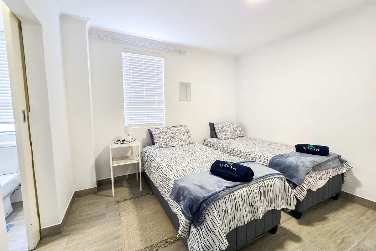 A bright bedroom featuring tiled flooring, white walls, and an en-suite bathroom access, providing a clean and functional living space.