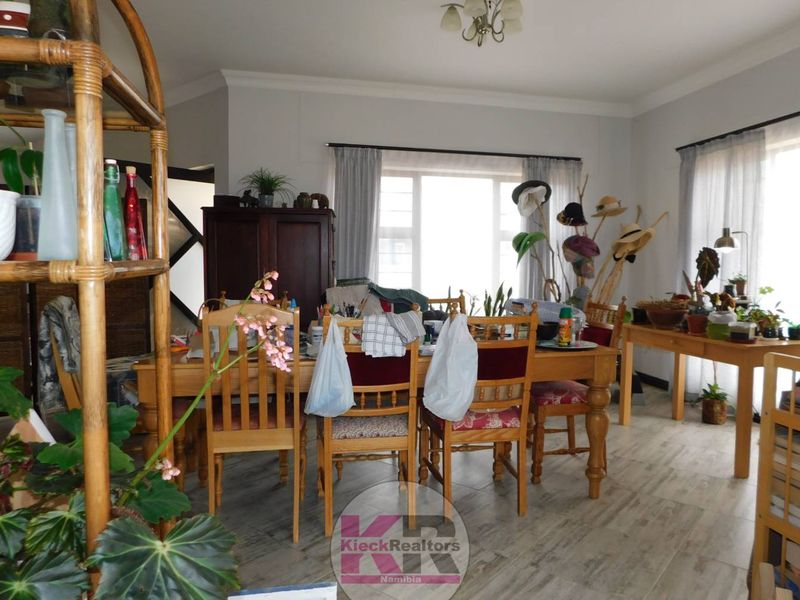 A dining room featuring tiled flooring, cove cornicing, and large windows that provide ample natural light to the space.