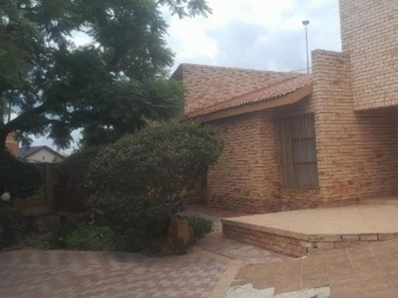 Rear exterior view of a face brick house featuring a paved patio area and established garden surroundings.