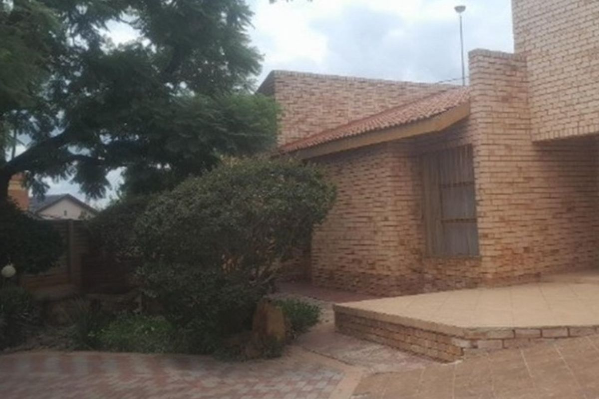 Rear exterior view of a face brick house featuring a paved patio area and established garden surroundings.