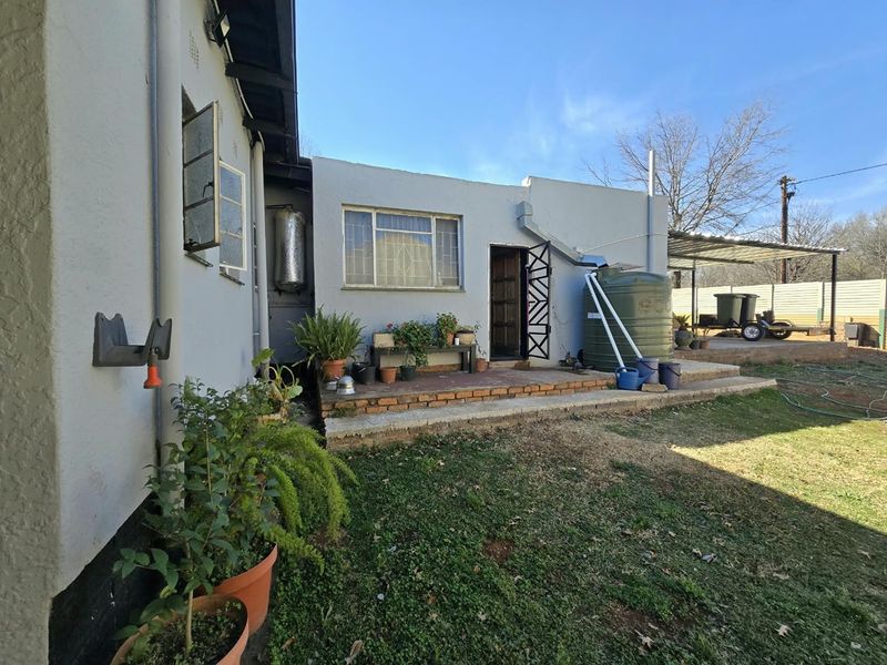 Rear exterior view of the property featuring a brick patio, water storage tank, and direct access to the backyard area.
