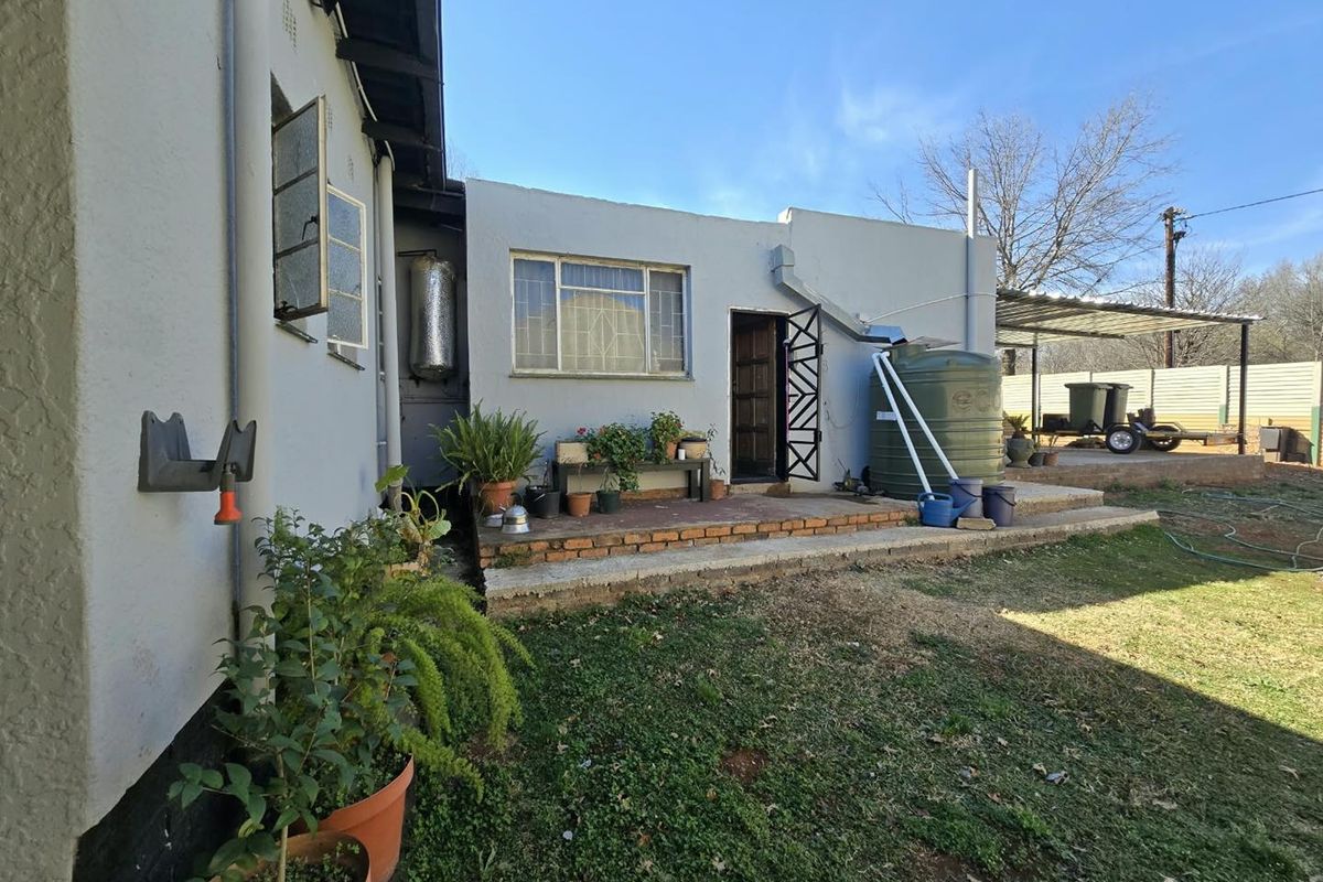 Rear exterior view of the property featuring a brick patio, water storage tank, and direct access to the backyard area.