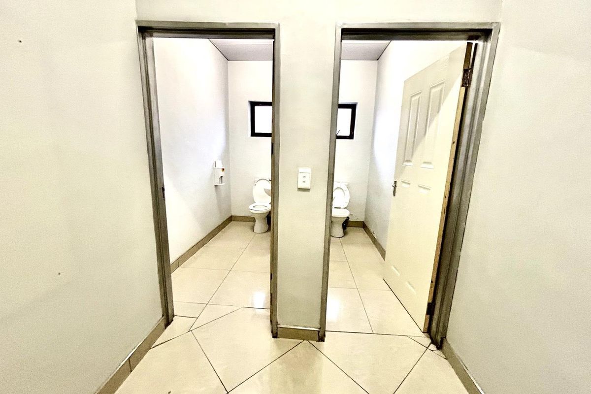 A functional office restroom facility featuring two separate toilet cubicles with tiled flooring and standard sanitary fixtures.