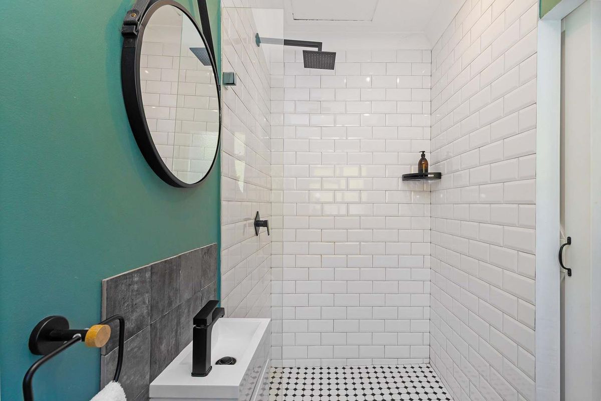 Modern bathroom featuring a walk-in shower with white subway tiles, a rain shower head, and a stylish vanity basin with matte black fixtures.