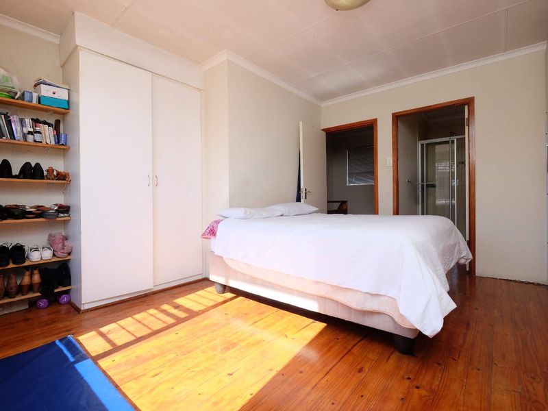 Bedroom featuring timber flooring, built-in wardrobe storage, and direct access to an en-suite bathroom.
