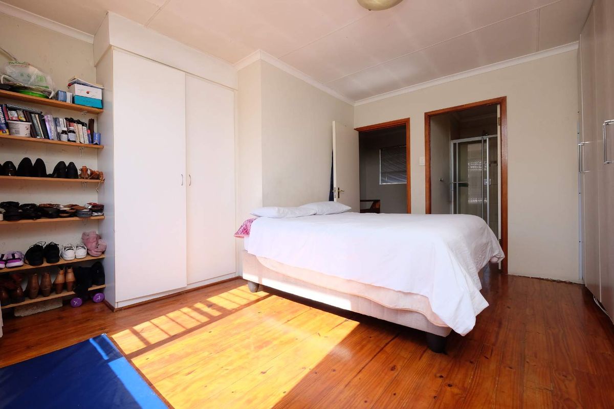 Bedroom featuring timber flooring, built-in wardrobe storage, and direct access to an en-suite bathroom.
