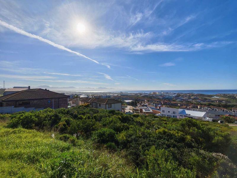 A scenic elevated view overlooking a residential neighbourhood with distant coastal and mountain vistas.
