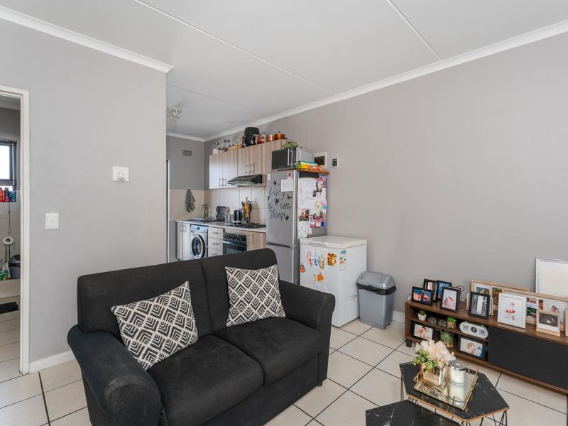 Open-plan living area featuring a compact kitchen with built-in cabinetry and an adjacent bathroom with standard fixtures.