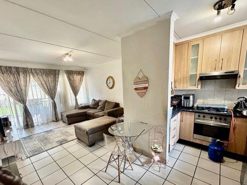Open-plan living area featuring tiled floors, a functional kitchen with built-in cabinetry, gas stove, and direct access to an outdoor space via sliding doors.