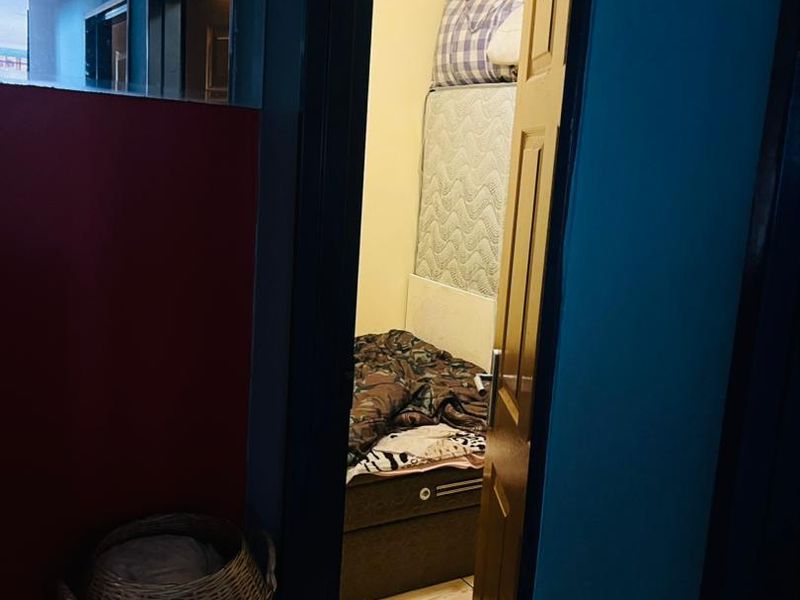 A view into a compact bedroom featuring tiled flooring, accessed through a doorway from an adjacent hallway.