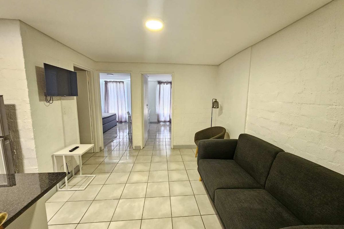 A view of the living area featuring tiled flooring and access to adjacent rooms, with a neutral interior finish.