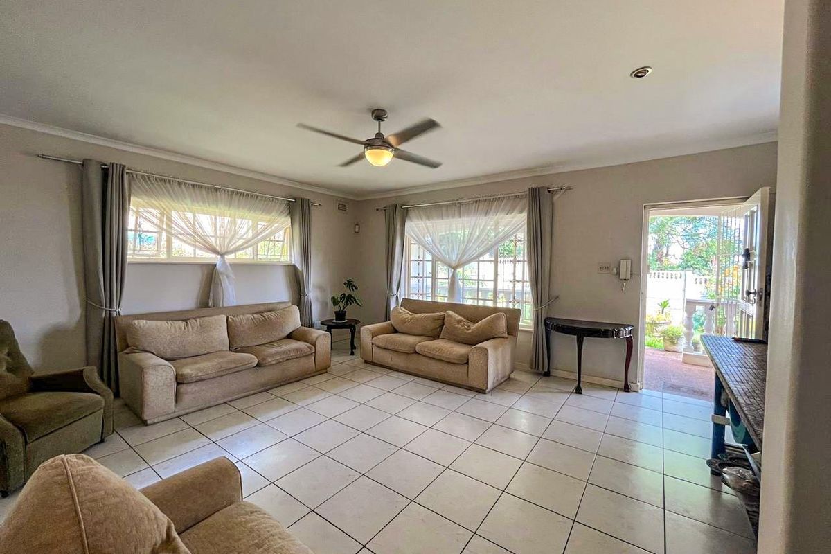 Spacious living room featuring neutral ceramic floor tiles, a ceiling fan, and direct access to an outdoor patio area.