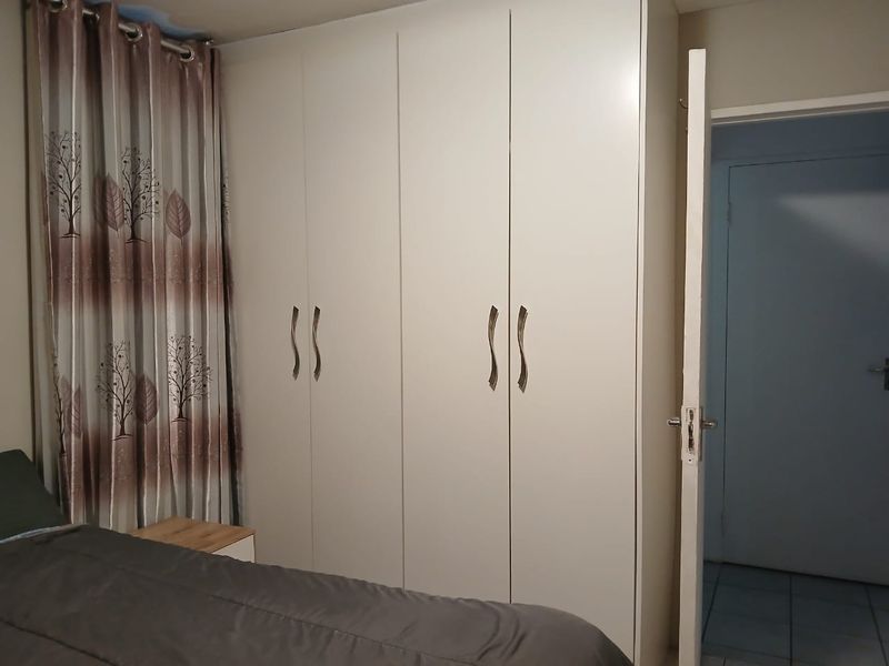 A bedroom featuring a large, white built-in wardrobe with modern handles, providing ample storage space.