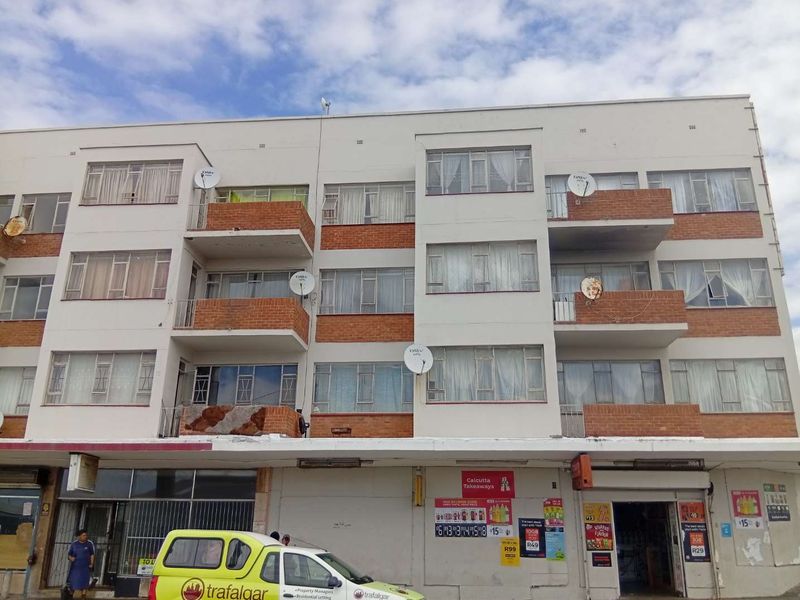 Front elevation of a multi-story apartment building featuring brick balconies, aluminium windows, and ground-floor commercial retail space.