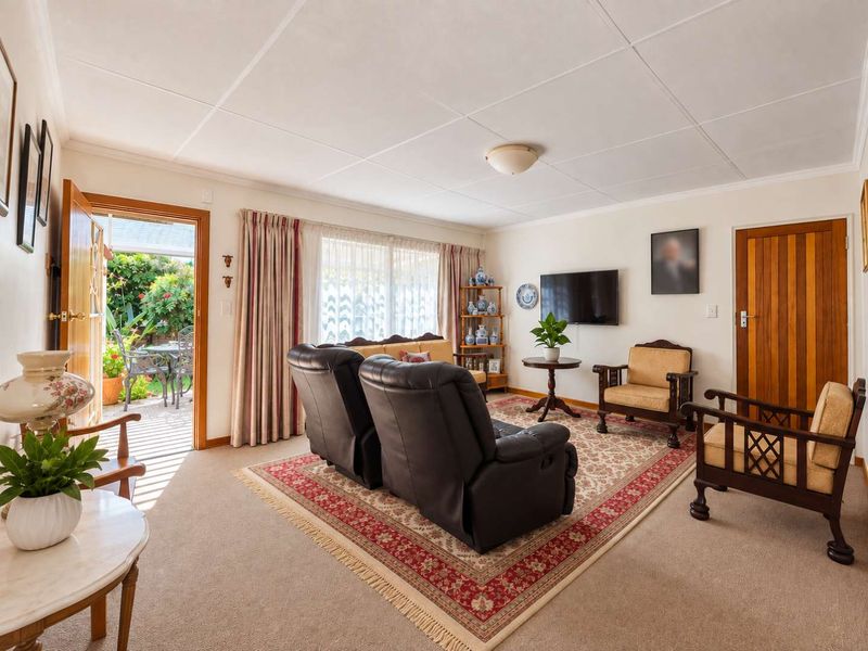 A comfortable living room featuring carpeted flooring, a tiled ceiling, and direct access to an outdoor patio area through a sliding glass door.