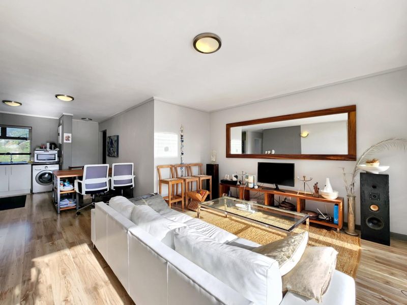 Open-plan living area featuring laminate flooring and integrated kitchen space with laundry facilities, offering a functional and versatile layout for modern apartment living.