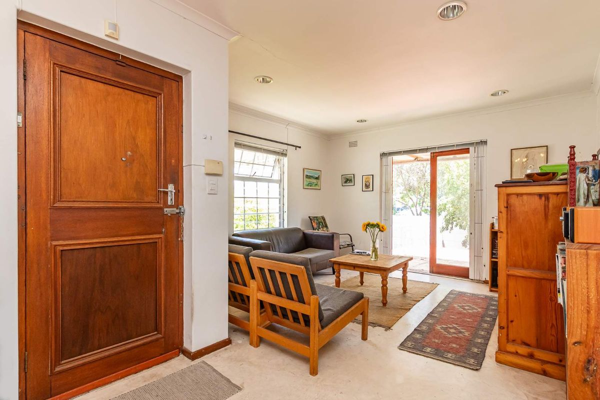 A living room featuring a solid timber entrance door, recessed downlighting, and sliding glass doors providing direct access to the outdoor patio area.
