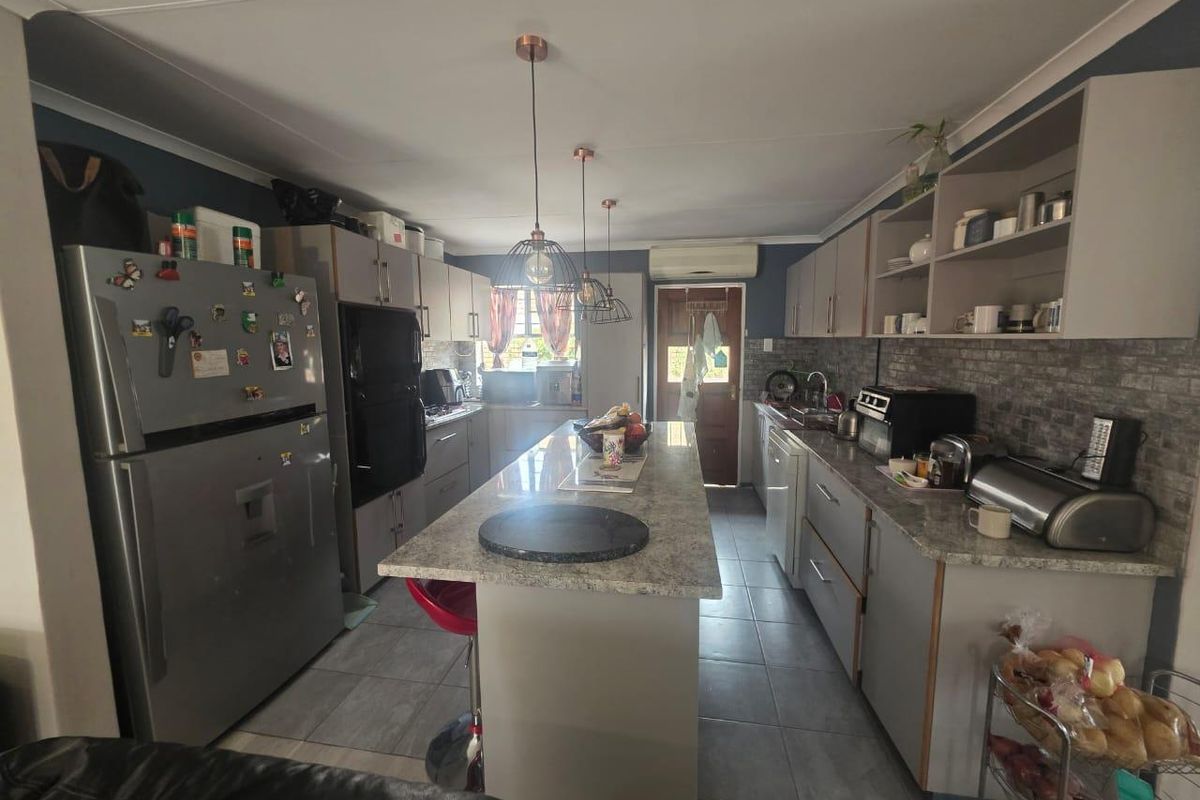 A functional kitchen featuring a central island, stone-look countertops, built-in cabinetry, and tiled flooring, providing a practical workspace for daily meal preparation.