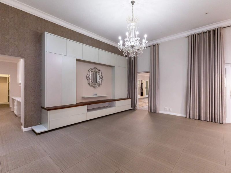 Spacious living room featuring large-format floor tiles, a decorative chandelier, and extensive built-in cabinetry with a media console.