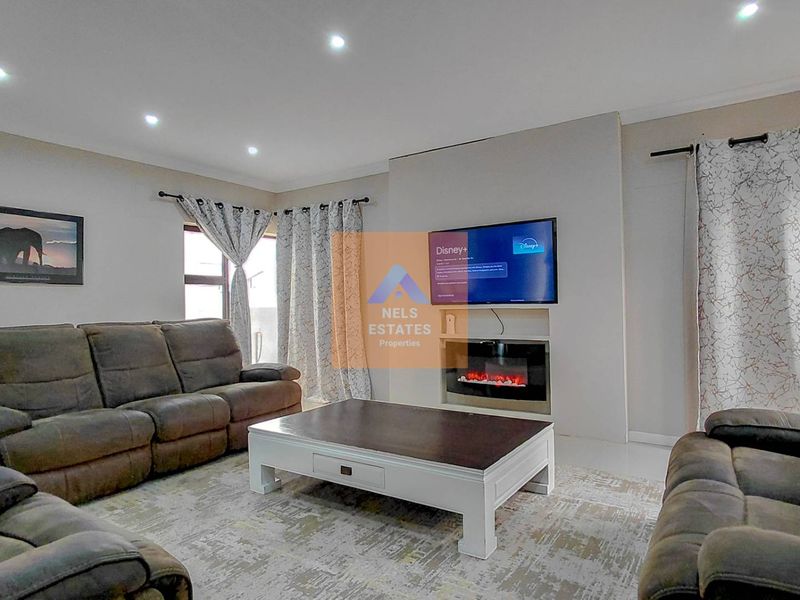 A comfortable living room featuring a modern built-in electric fireplace, recessed downlighting, and neutral tiled flooring.