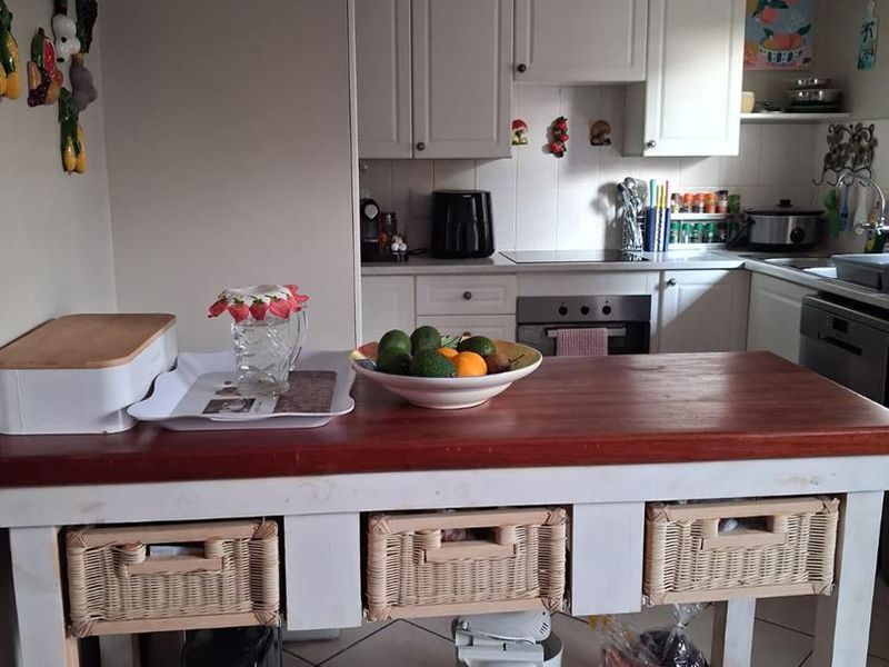 A functional kitchen featuring white cabinetry, built-in oven and hob, and tiled flooring, providing a practical workspace with ample storage.