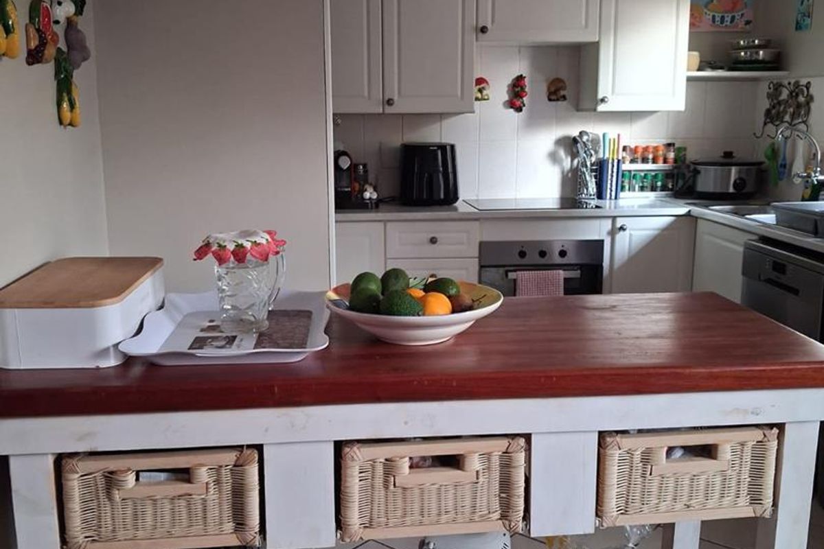 A functional kitchen featuring white cabinetry, built-in oven and hob, and tiled flooring, providing a practical workspace with ample storage.