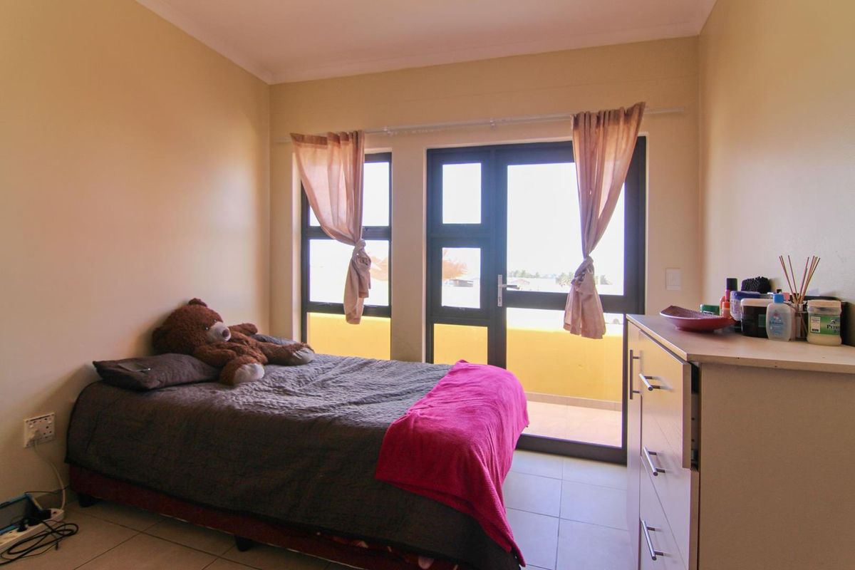 A bedroom featuring tiled flooring and a glass door providing access to a private balcony.
