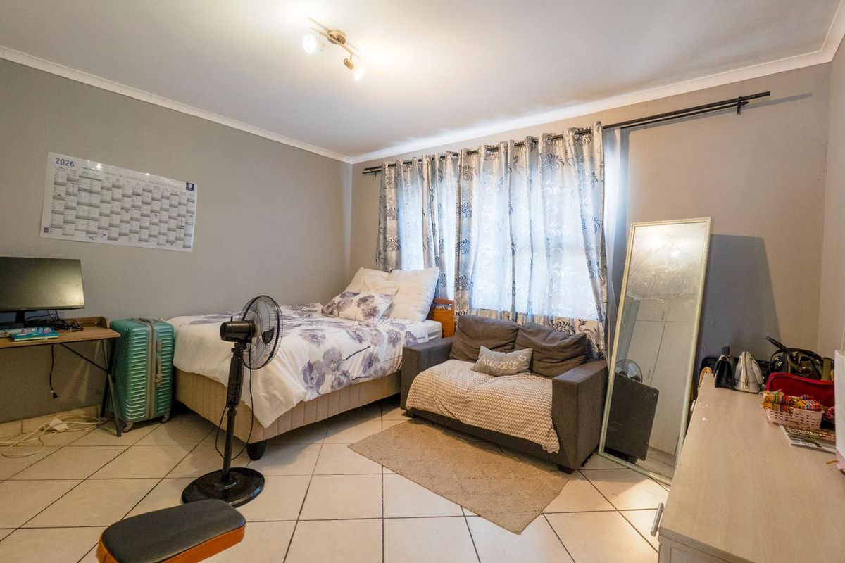 A bedroom featuring tiled flooring, neutral wall paint, and a window with curtain tracks.