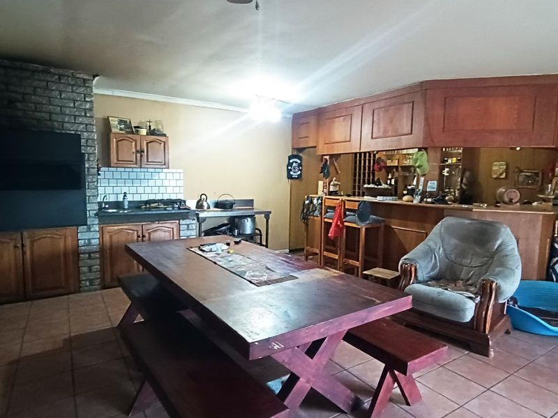 Open plan living and entertainment area featuring a brick fireplace, built-in bar counter, and tiled flooring throughout.