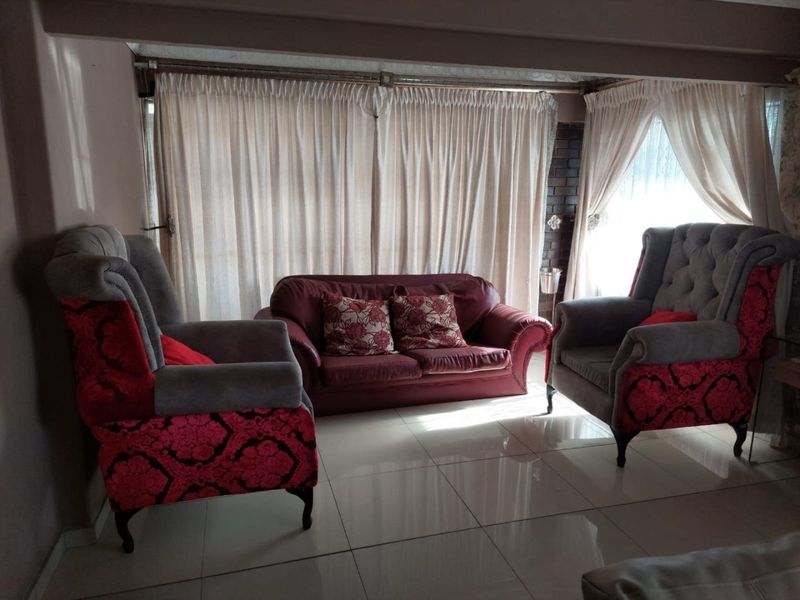 A living room area featuring polished floor tiles and large windows covered by curtains, providing a neutral base for interior design updates.