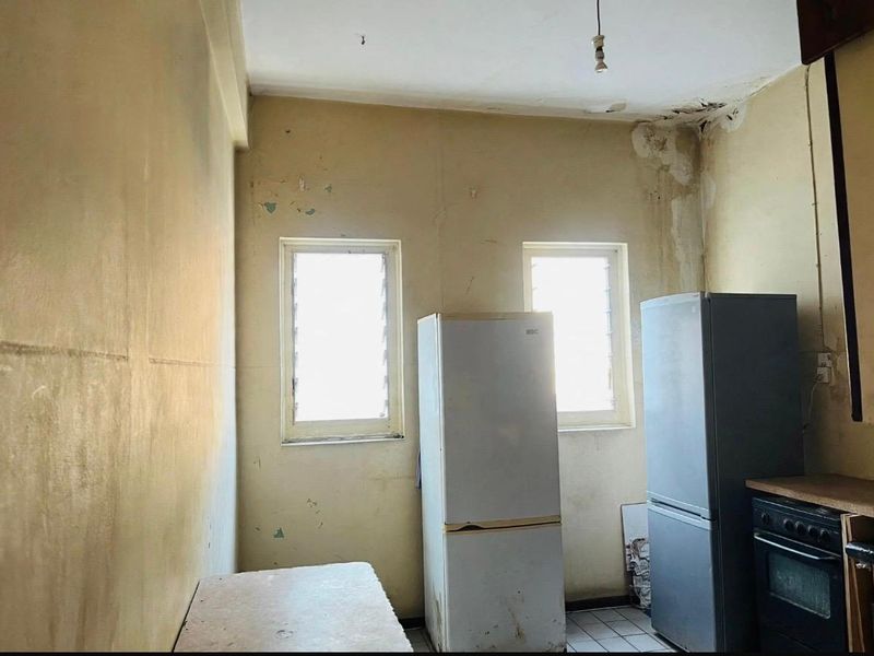 A kitchen space in poor condition showing significant water damage on the ceiling and walls, requiring extensive renovation and repair of fixed finishes.