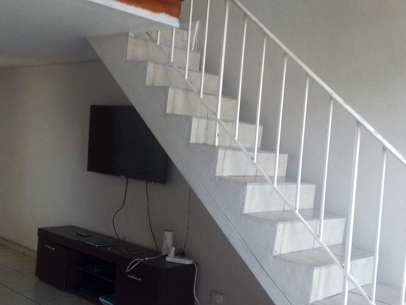 Living area featuring a staircase with a metal balustrade and tiled flooring, providing access to the upper level of the apartment.