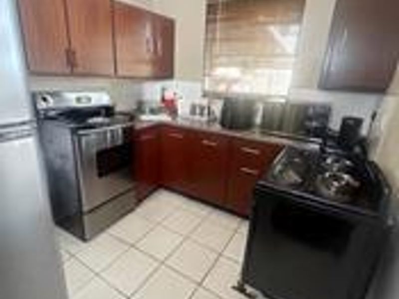 A functional kitchen featuring dark wood cabinetry, tiled flooring, and a stainless steel stove, offering a practical layout for daily meal preparation.