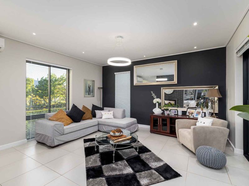 A well-maintained living room featuring tiled flooring, recessed downlighting, a split-system air conditioner, and large sliding glass doors providing natural light.