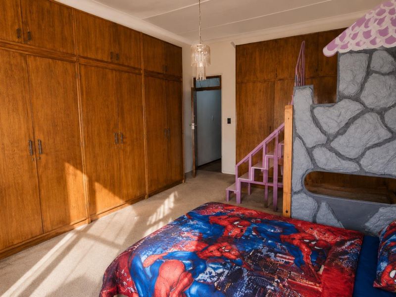 A bedroom featuring extensive wall-to-wall built-in wooden cabinetry, carpeted flooring, and a central light fixture.