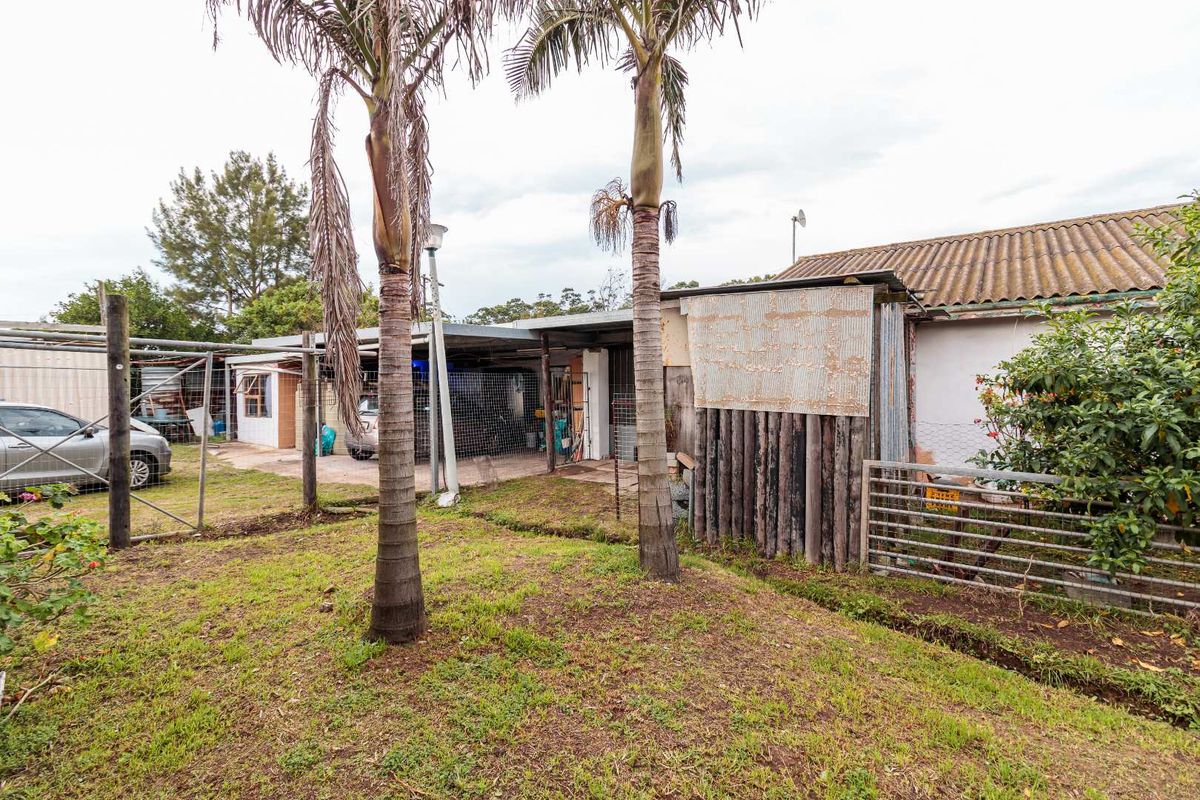 Rear exterior view of the small holding featuring a concrete slab area, corrugated iron structures, and perimeter wire and timber fencing.