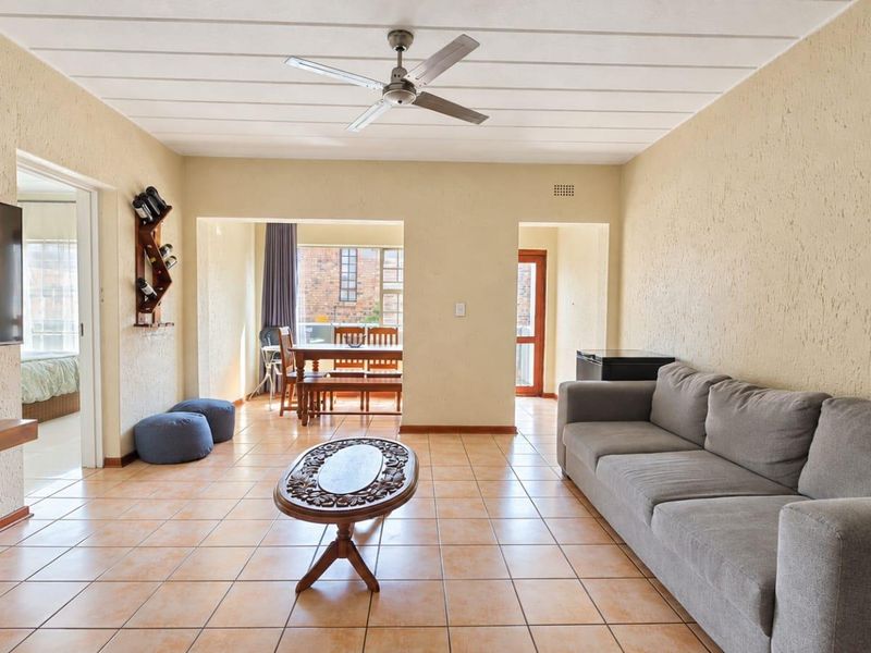 Open-plan living and dining area featuring tiled flooring, textured walls, and a ceiling fan, providing a functional and connected living space.