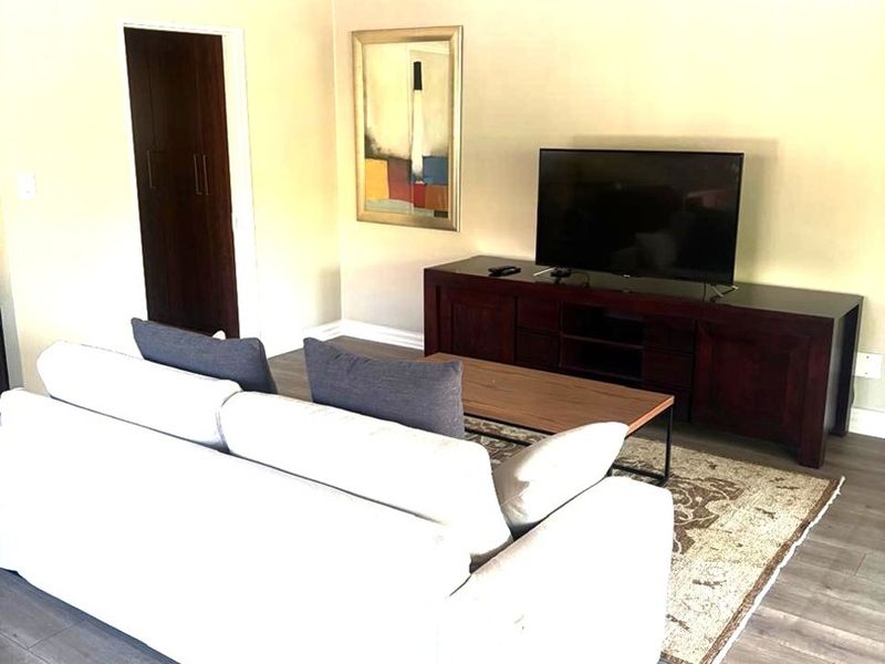 A bright living room featuring vaulted ceilings, modern laminate flooring, and a neutral color palette, creating an open and inviting atmosphere.