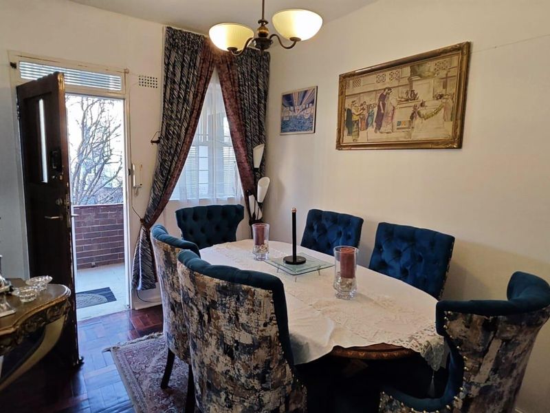 A dining room featuring classic parquet flooring and direct access to an outdoor balcony area.