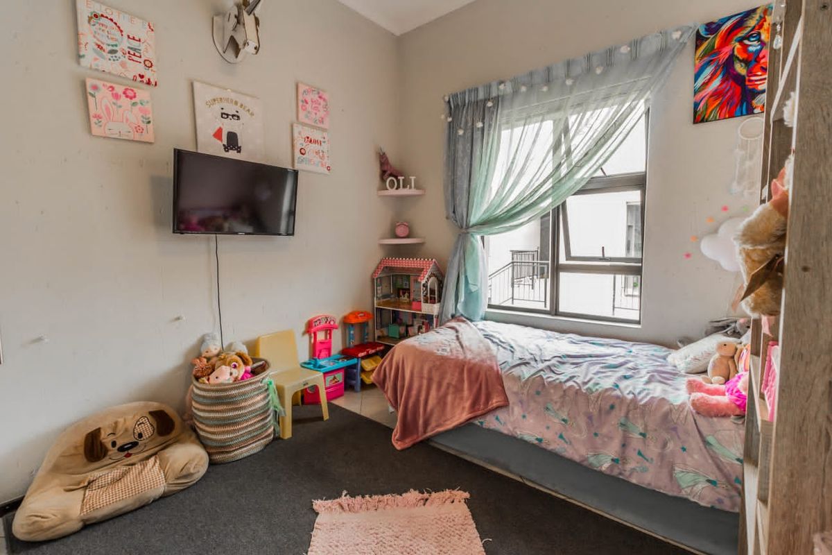 A functional bedroom featuring carpeted flooring and an aluminium-framed window, providing natural light and a comfortable living space.