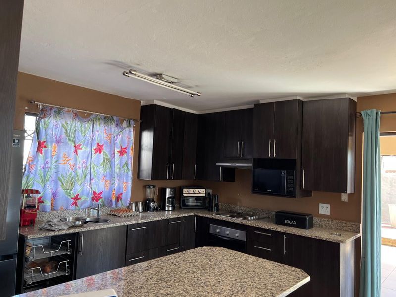 A functional kitchen featuring dark wood cabinetry, granite countertops, a built-in oven, and an extractor fan.