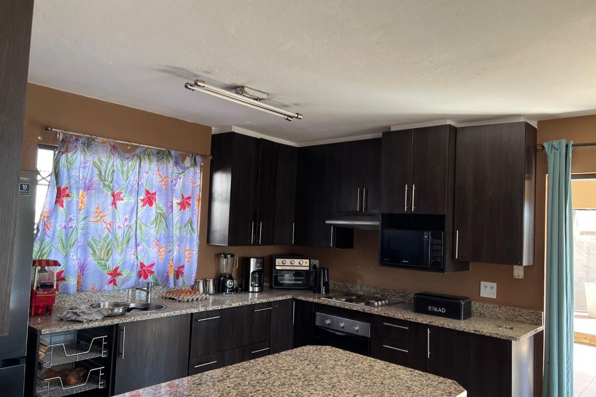 A functional kitchen featuring dark wood cabinetry, granite countertops, a built-in oven, and an extractor fan.