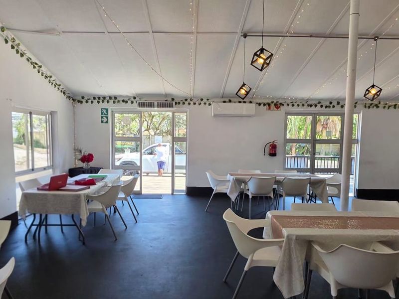 Open-plan commercial space featuring exposed beam ceilings, pendant lighting, and split-system air conditioning, suitable for dining or event hosting.