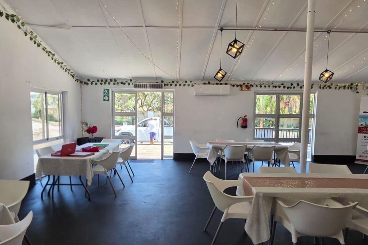 Open-plan commercial space featuring exposed beam ceilings, pendant lighting, and split-system air conditioning, suitable for dining or event hosting.