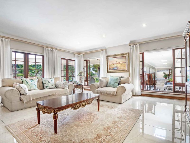 Spacious living room featuring polished tiled flooring, recessed downlights, and multiple timber-framed glass doors providing natural light and access to the outdoor area.