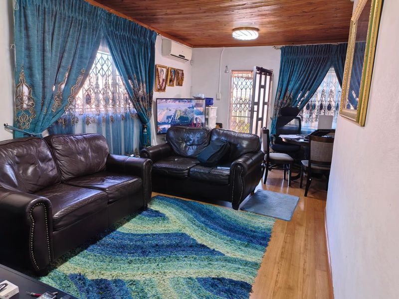 A living room featuring timber ceilings, laminate flooring, and security bars on the windows, providing a functional and secure living space.