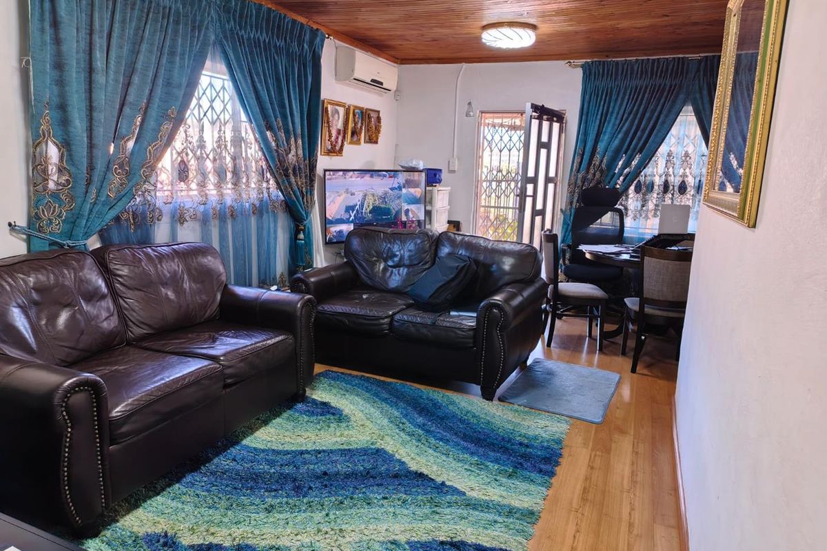 A living room featuring timber ceilings, laminate flooring, and security bars on the windows, providing a functional and secure living space.