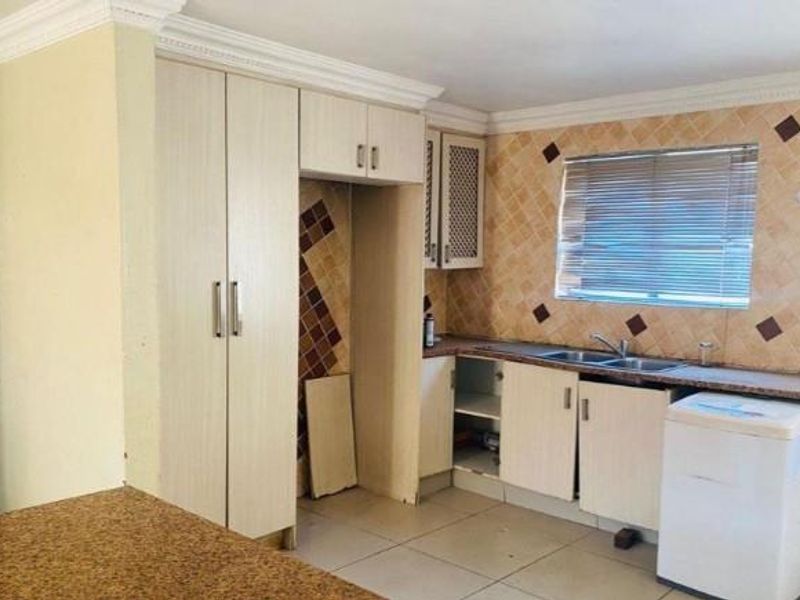 A functional kitchen featuring built-in cabinetry, a double sink, and a tiled backsplash, offering potential for modernization and cosmetic updates.