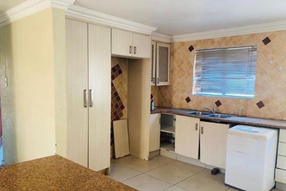 A functional kitchen featuring built-in cabinetry, a double sink, and a tiled backsplash, offering potential for modernization and cosmetic updates.